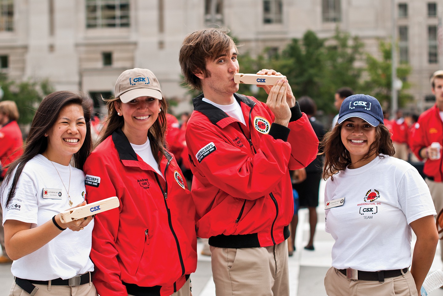 Four AmeriCorps members wearing and holding CSX branded items