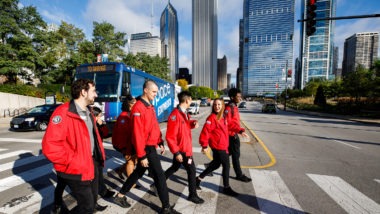 A group of AmeriCorps members in the city cross the street in the crosswalk.