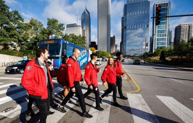 A group of AmeriCorps members in the city cross the street in the crosswalk.