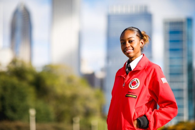 An AmeriCorps member stands in front of the city skyline.