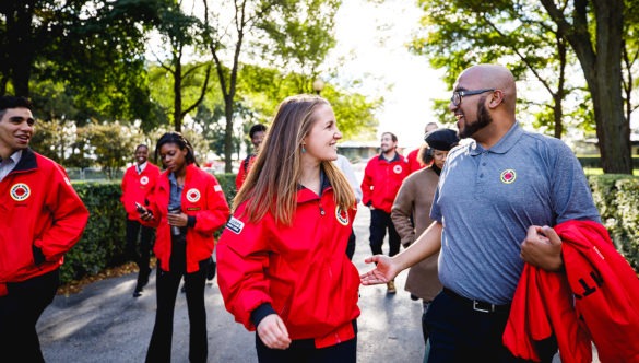 A group of AmeriCorps members walk together along a path in a park.