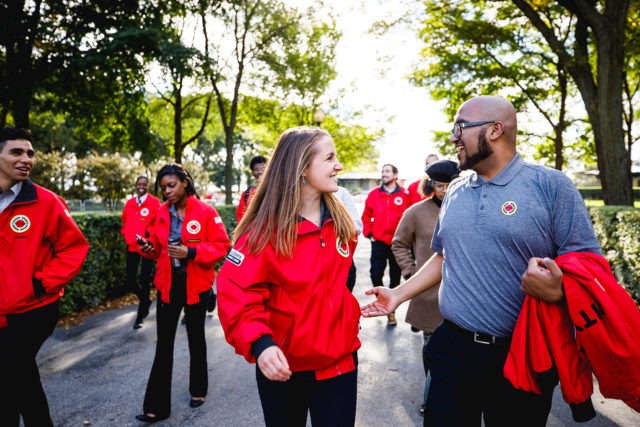 A group of AmeriCorps members walk together along a path in a park.