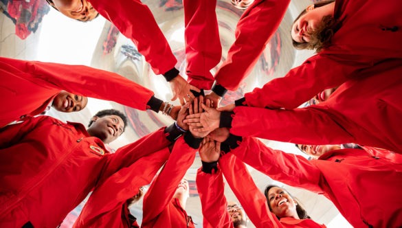 Twelve AmeriCorps members all putting their hands in a the center, getting ready to do a spirit break