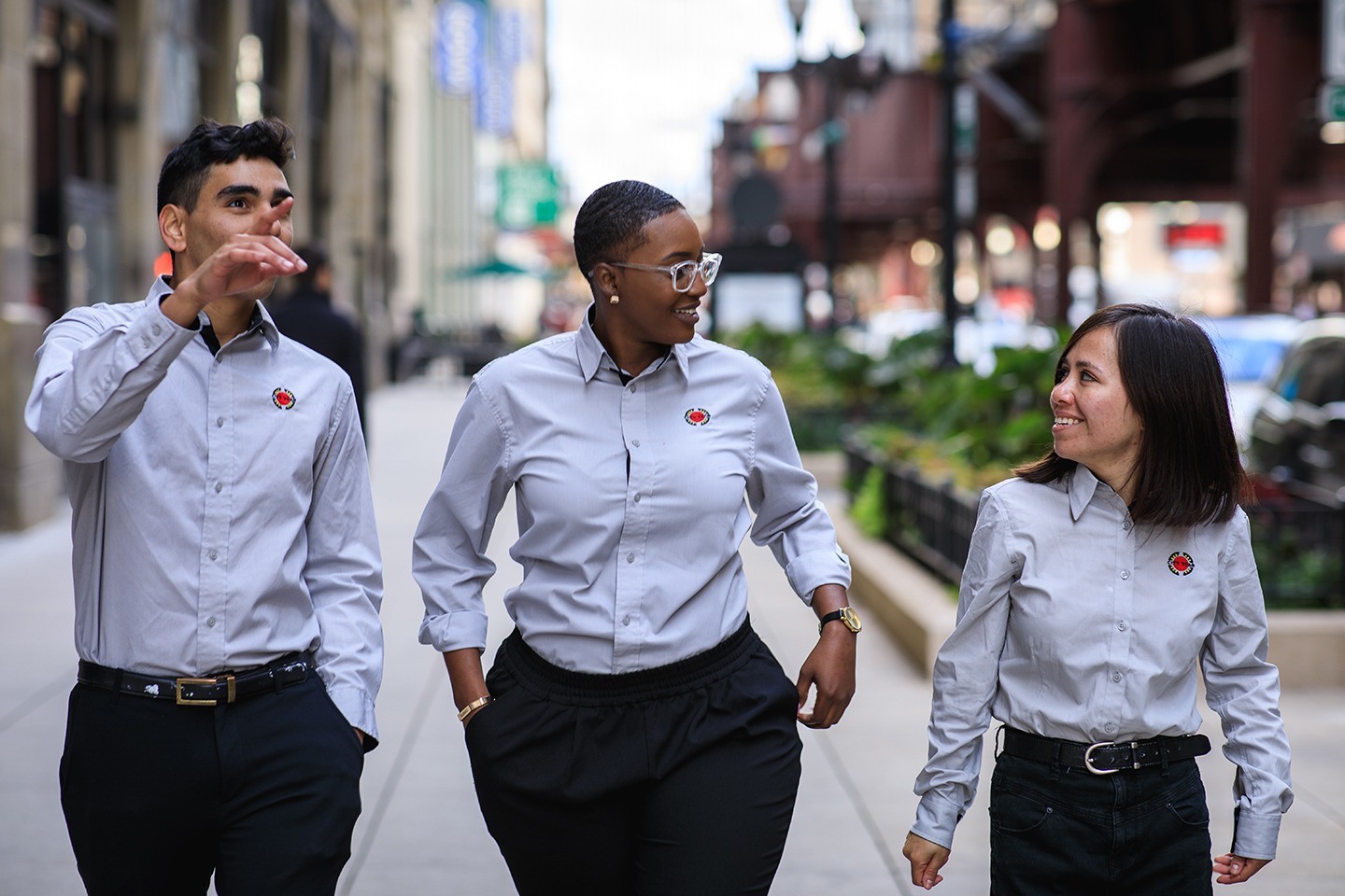 A group of AmeriCorps members walk along the city sidewalk.