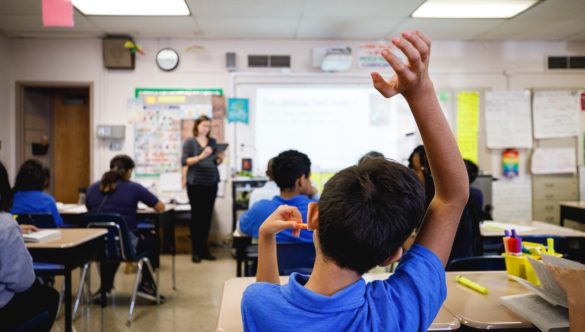 A group of students sit in their desks and listen to their teacher's lesson.