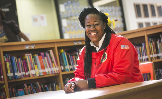 An AmeriCorps member sits at a table in a school library.