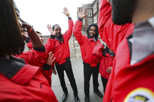 A team of City Year AmeriCorps members raise their hands at the end of a team huddle