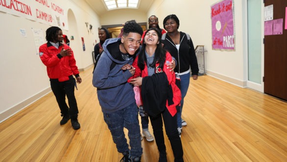 Group of laughing students and City Year corps members walking in a school hallway