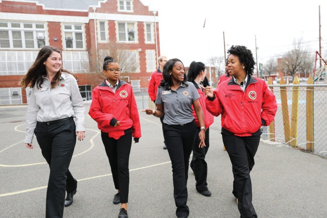 A group of AmeriCorps members chat as they walk across the school playground.