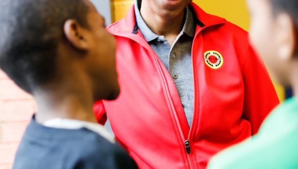 City year americorps member talking with two young students near a window in a school hallway