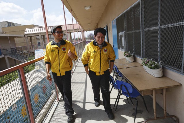 two AmeriCorps members walk together through hallway in conversation