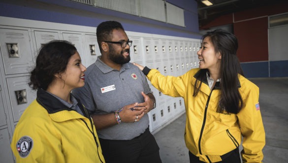 Three AmeriCorps members standing in front of lockers, talking