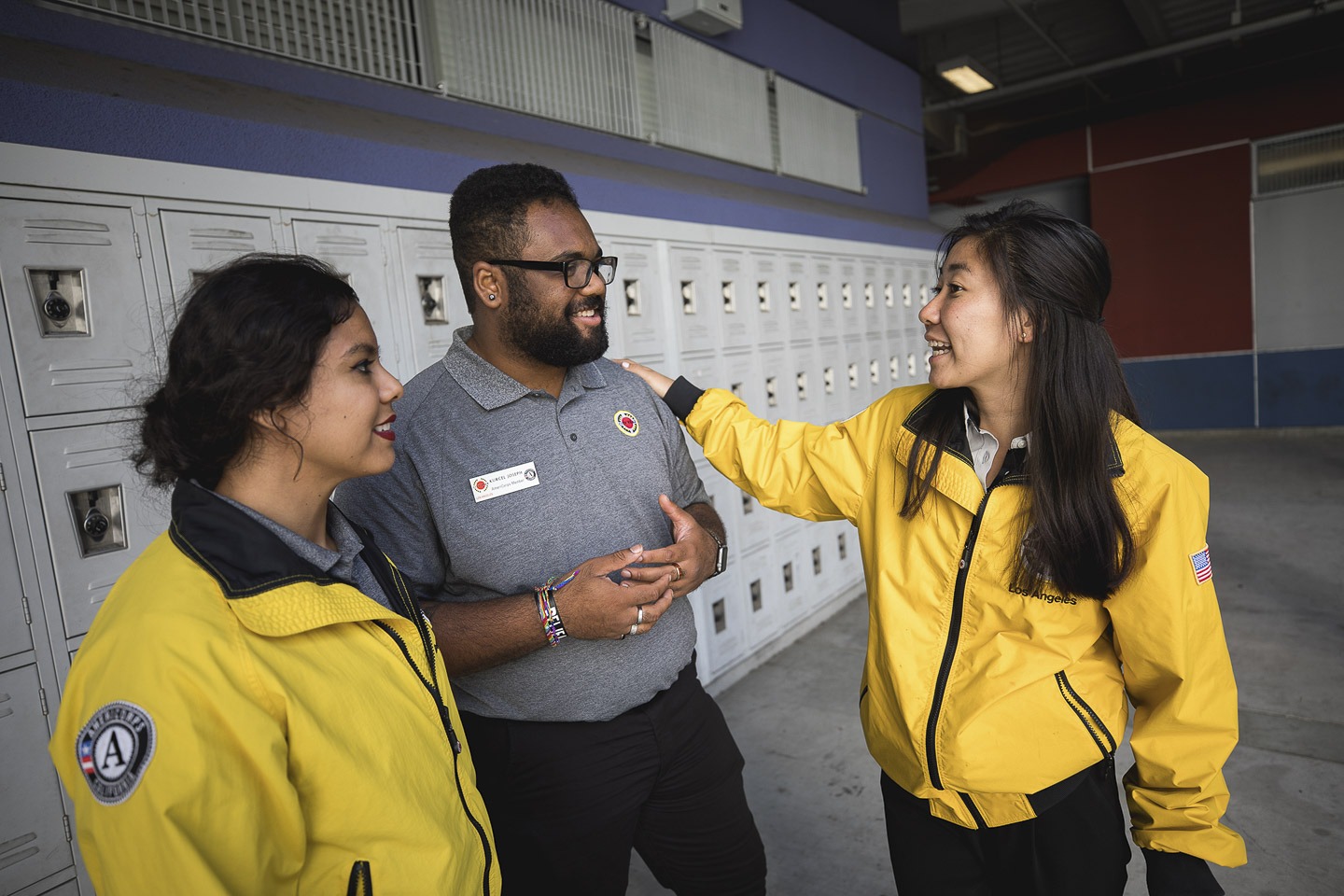 Three AmeriCorps members standing in front of lockers, talking
