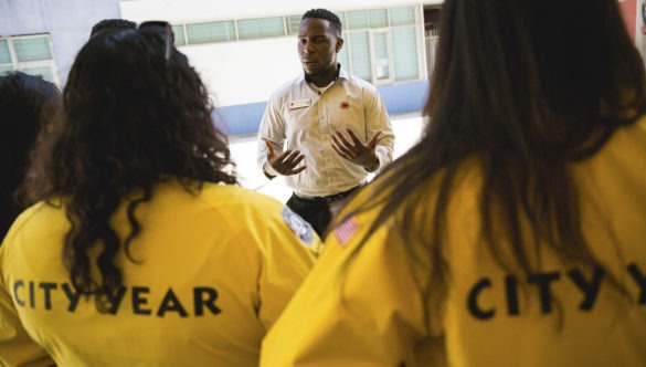 A Team Leader stands in front of his team, providing information and instructions for their day