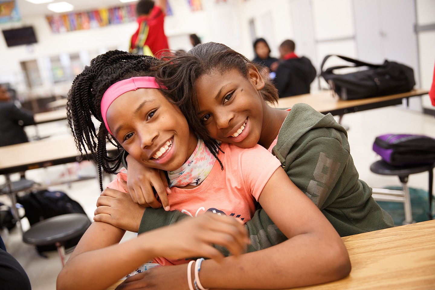 two students hug each other at their desks