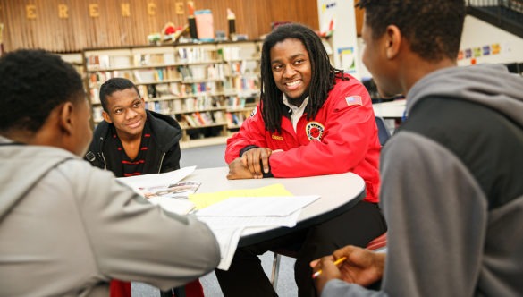 City year americorps member with three students sitting at a table in a school library