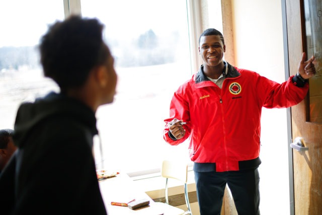 city year americorps member explains a lesson to a student as they stand facing a chalkboard