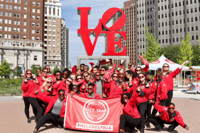 Philadelphia AmeriCorps members with flag at LOVE sign