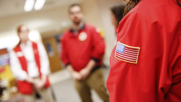 A group of AmeriCorps members stand together in circle in the classroom.