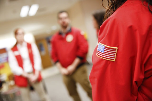 A group of AmeriCorps members stand together in circle in the classroom.