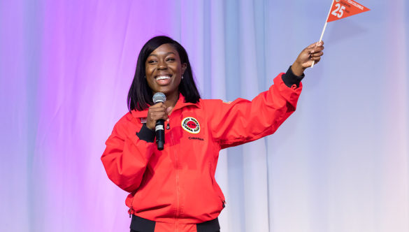 A smiling AmeriCorps member waves a pennant on stage