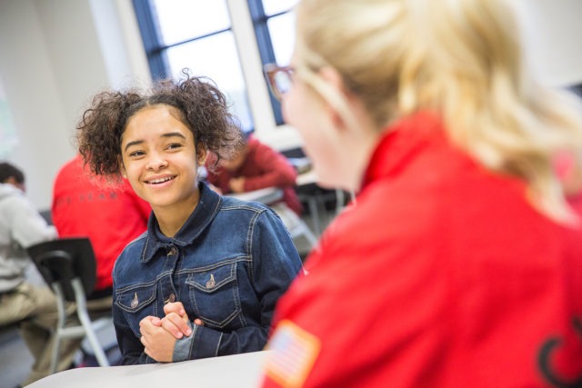 A young girl in a classroom taking with a City Year Americorps member