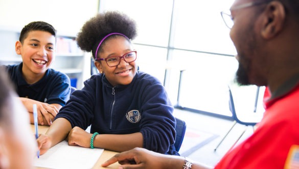 Two students writing at a table with a City Year mentor.