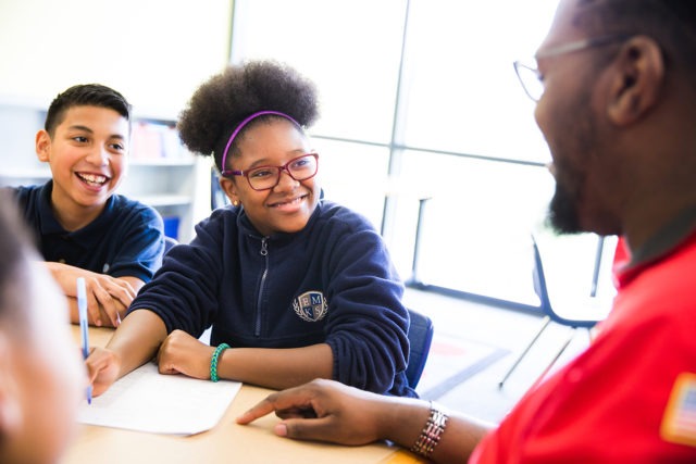 Two students writing at a table with a City Year mentor.