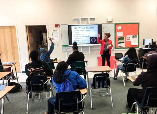 A City Year AmeriCorps member at the front of the classroom with students at their desks