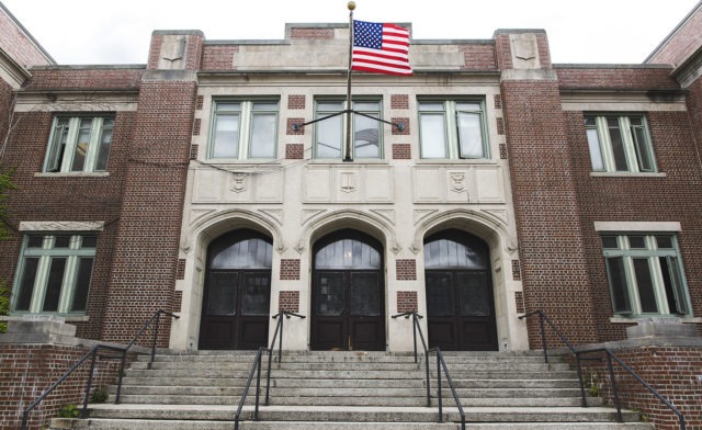 The entrance to a school with an American flag flying in the front.