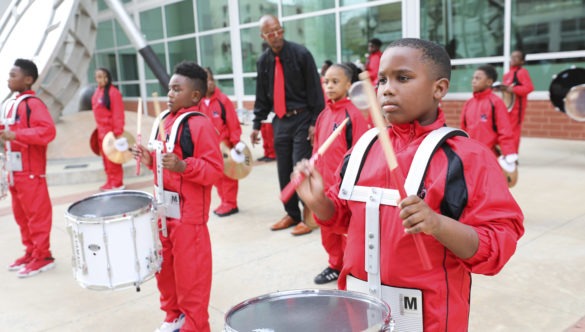 An elementary school marching band drums, dressed in red