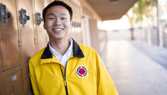 A City Year AmeriCorps member leans against lockers in a school hallway.