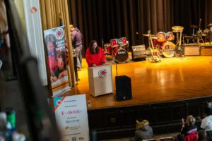 AmeriCorps member Jenny Roberts speaks from a podium on stage in an auditorium