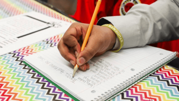 close up of student writing in a notebook