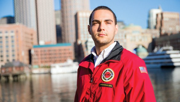 AmeriCorps member stands in front of the city skyline and water.