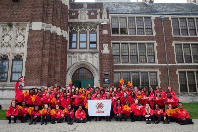 A City Year AmeriCorps member school team posts for a group photo in front of a school.