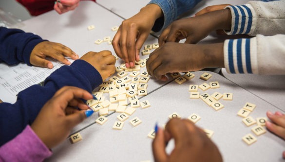 close up of children's hands during a game of scrabble