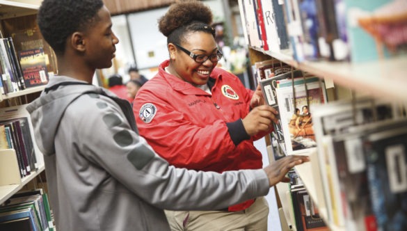 City Year AmeriCorps member in library with student