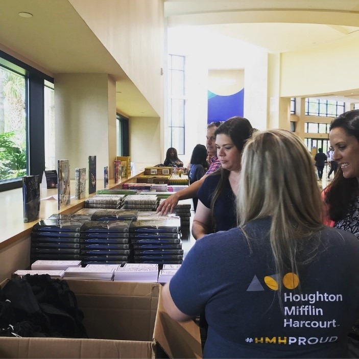 Volunteers from Hougton Mifflin Harcourt organize book donations for students