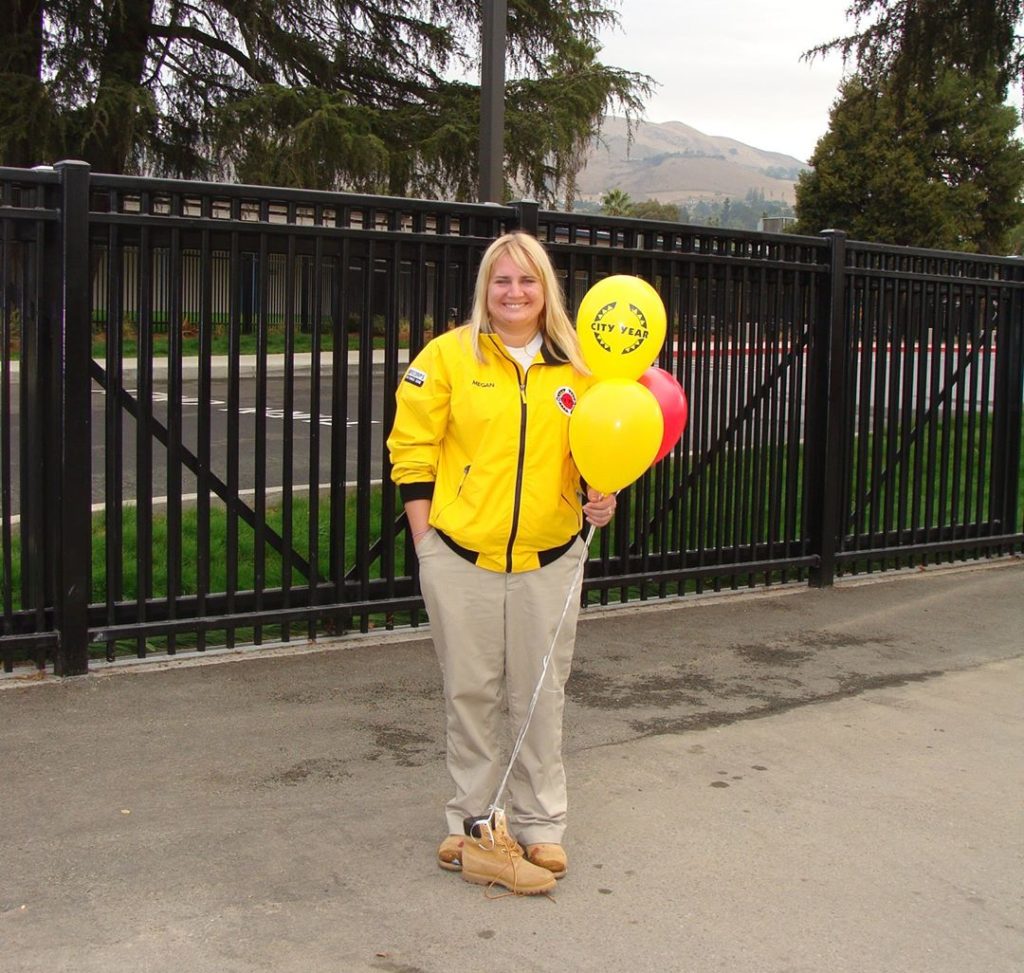 Megan Baker, City Year LA alum, stands in her yellow jacket holding balloons