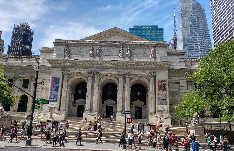 New York Public Library with people walking around the sidewalk in front.