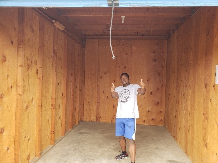 Senior AmeriCorps Member Mark Johnson stands proudly in the Storage Unit he has just emptied. 