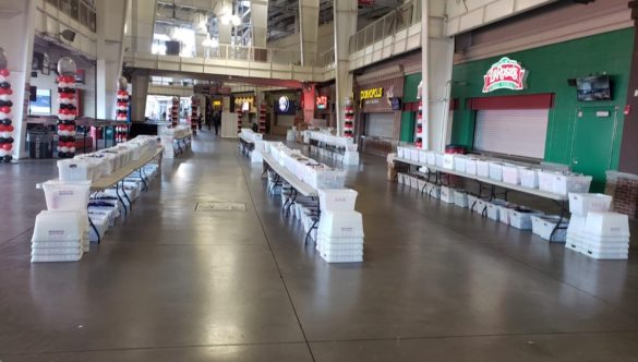 Three rows of tables with Operation Gratitude bins stacked on top. Each bin is filled with donated goods.
