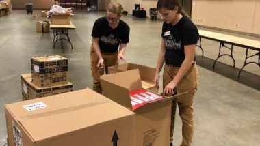 Two Care Force Members opening cardboard boxes with toys inside.