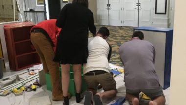 TCF Member Nana Boateng is working with volunteers to lead them in reading the schematic and building the four remaining bookshelves.