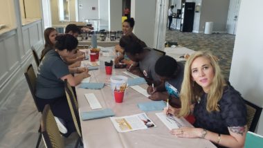 Tara, Cautchy, Alice, Ben, Delaney, Nana and Annie from HMH are decorating mural tiles to use as examples for the volunteers before the event kicks off.