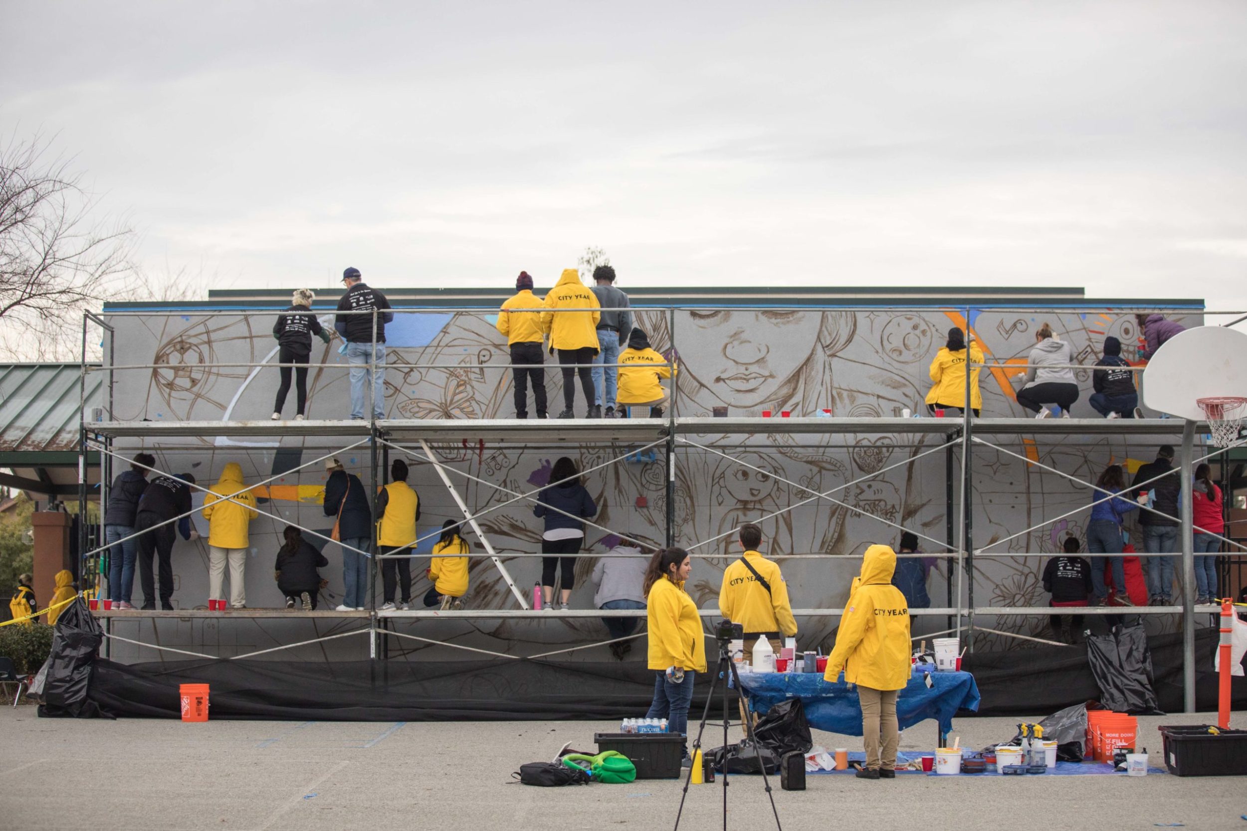 City Year AmeriCorps members and community volunteers paint a large mural at San Antonio Elementary School for MLK Day of Service