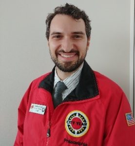 Head shot of Care Force alumni Warren Balsa wearing the iconic red City Year bomber with his nametag.