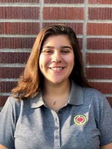 Headshot of Senior AmeriCorps Member Molly Rogers smiling in the grey City Year polo with a brick background.