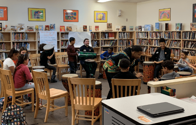 Students and AmeriCorps members participating in drumming during their Black History Month celebration. 